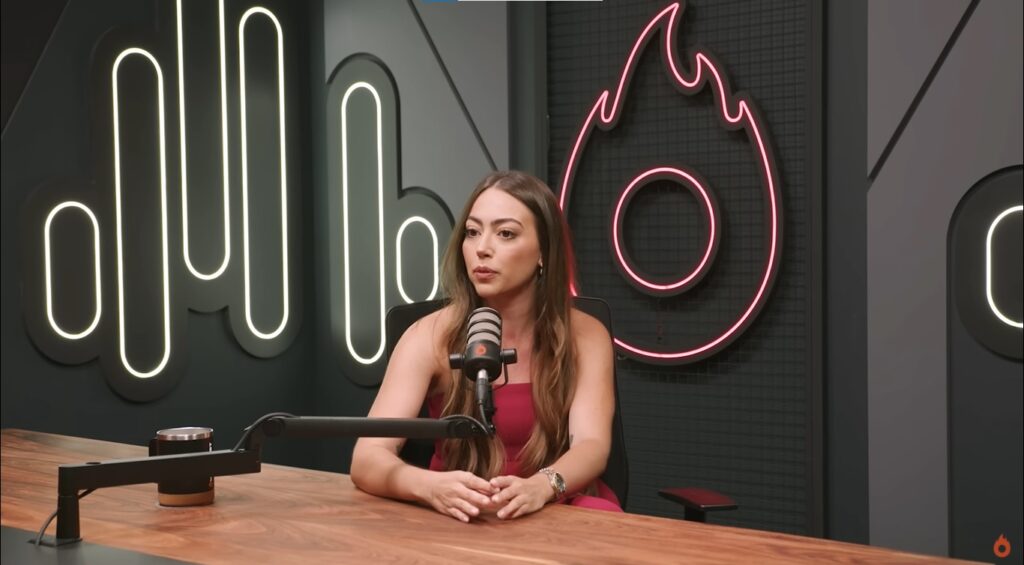 Mulher digitando no notebook com celular ao lado